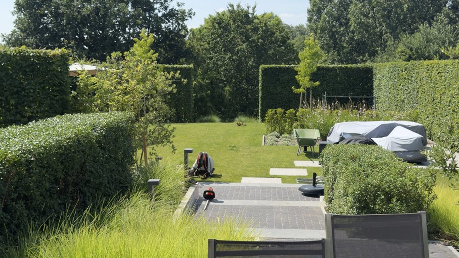Strak aangelegd terras met siergrassen en geschoren hagen